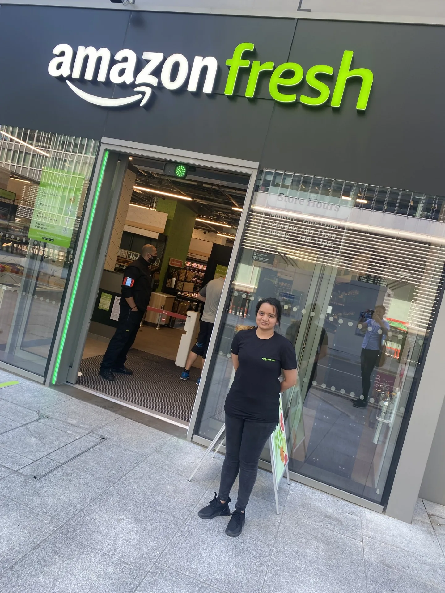 FOTS brand ambassador in an Amazon Fresh T-shirt outside an Amazon Fresh store entrance