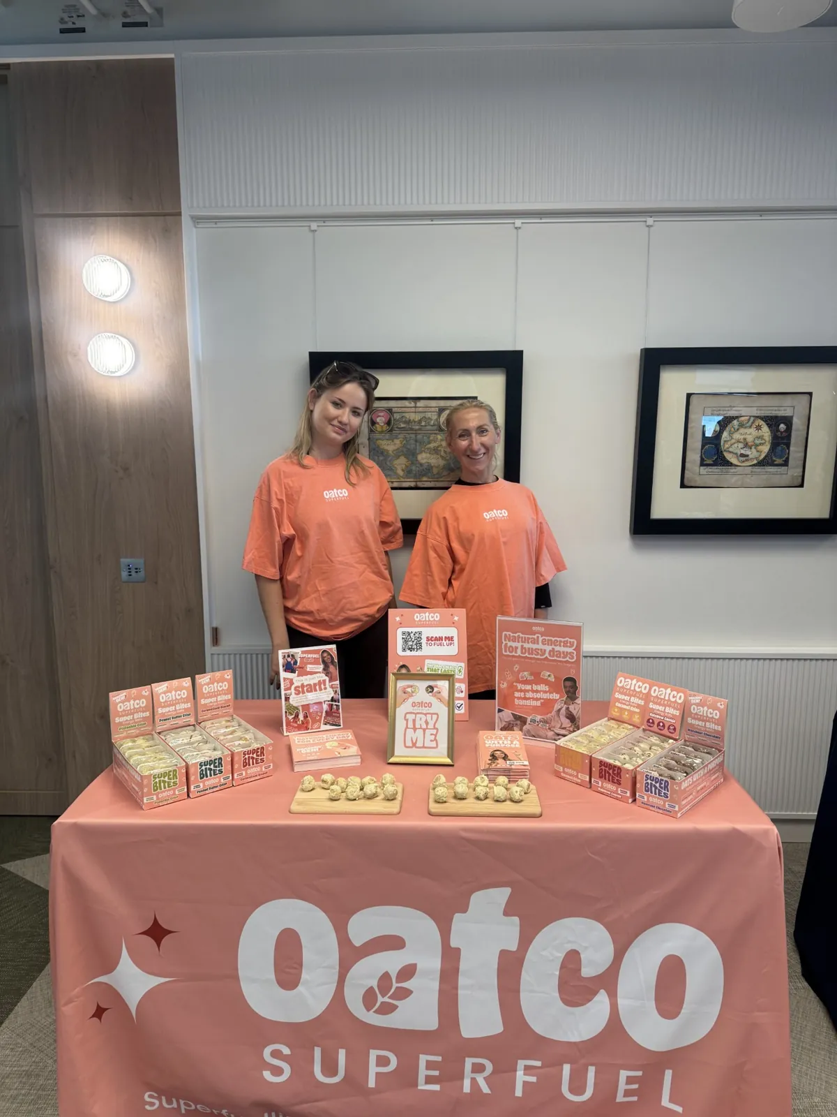 Two FOTS ambassadors in Oatco T-shirts behind a tasting table of Super Bites energy balls