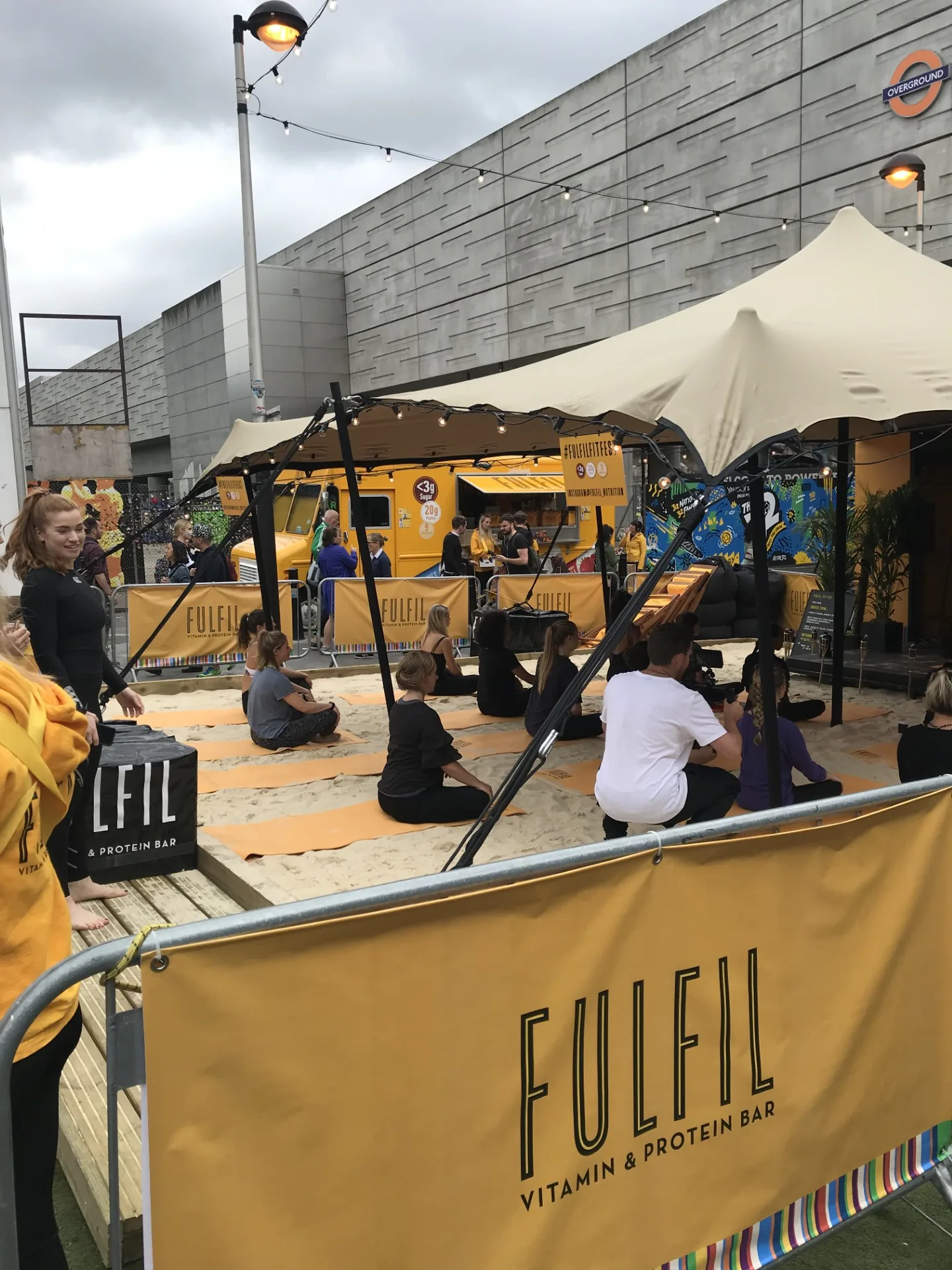 Guests on yoga mats at the Fulfil Fest beach-themed event space with the branded truck and stretch tent