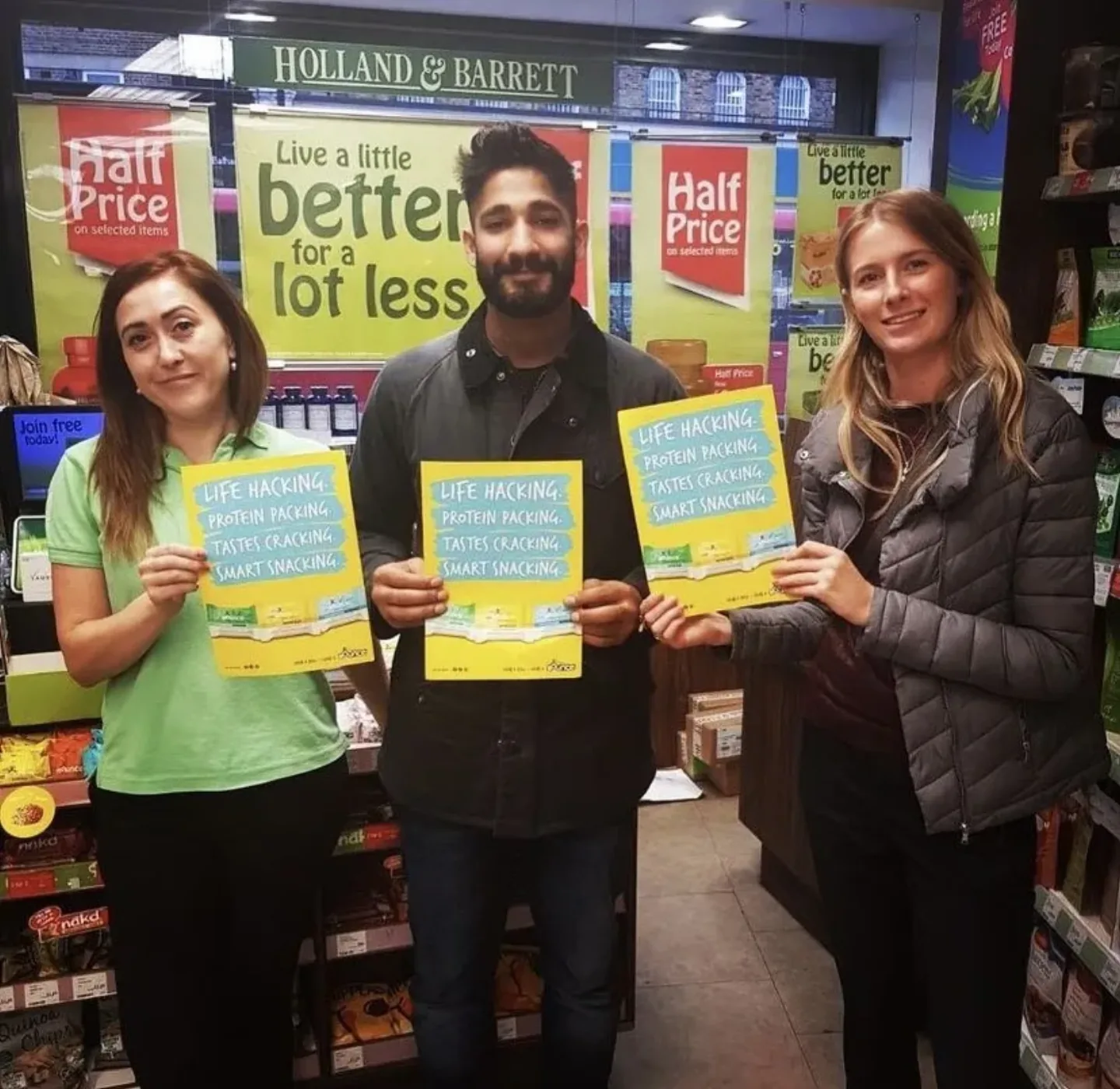 FOTS team holding snack promotion posters inside a Holland & Barrett store