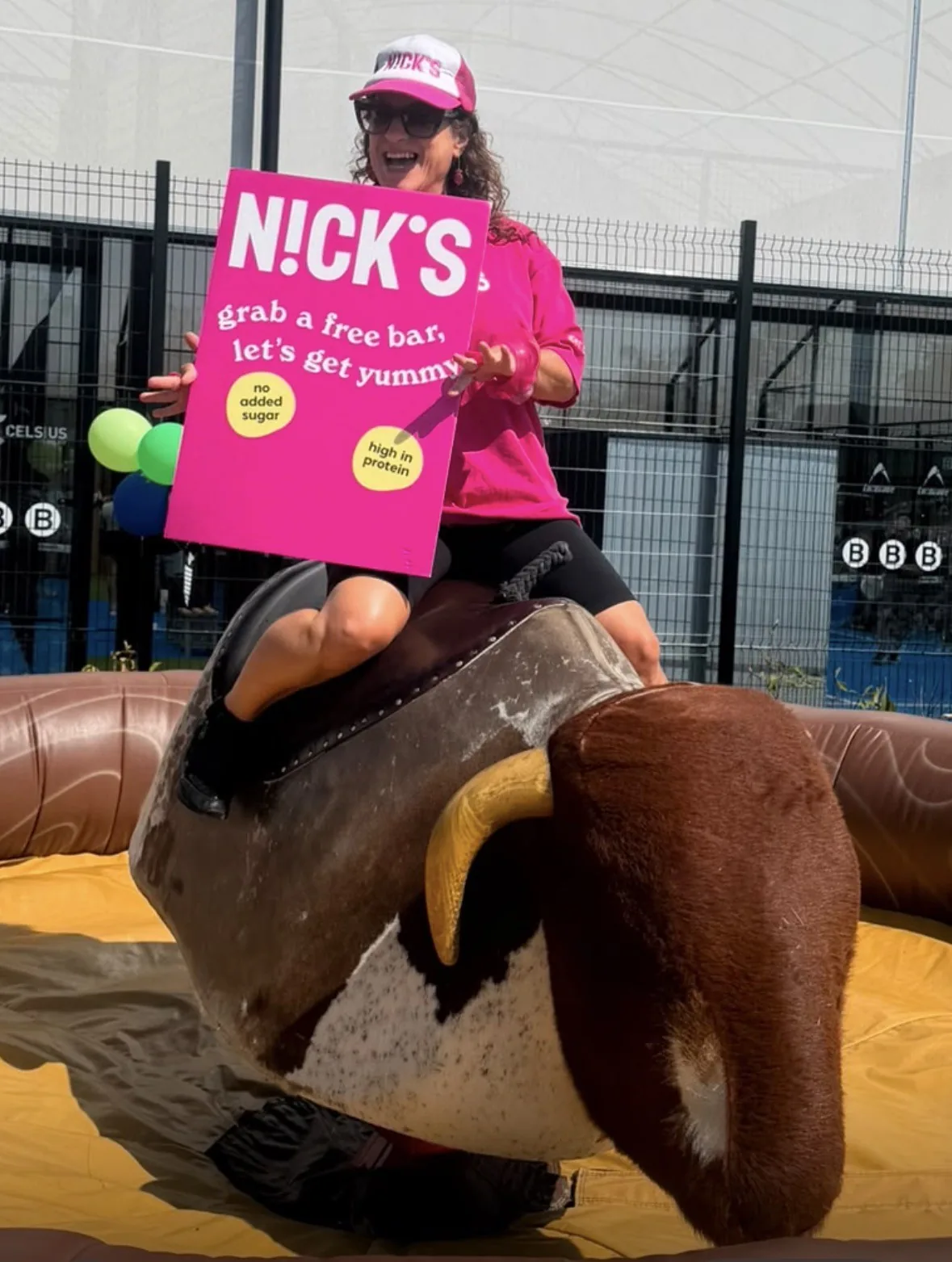 Brand Activation: FOTS ambassador riding a rodeo bull while holding a Nick's 'grab a free bar, let's get yummy' sign at an outdoor event