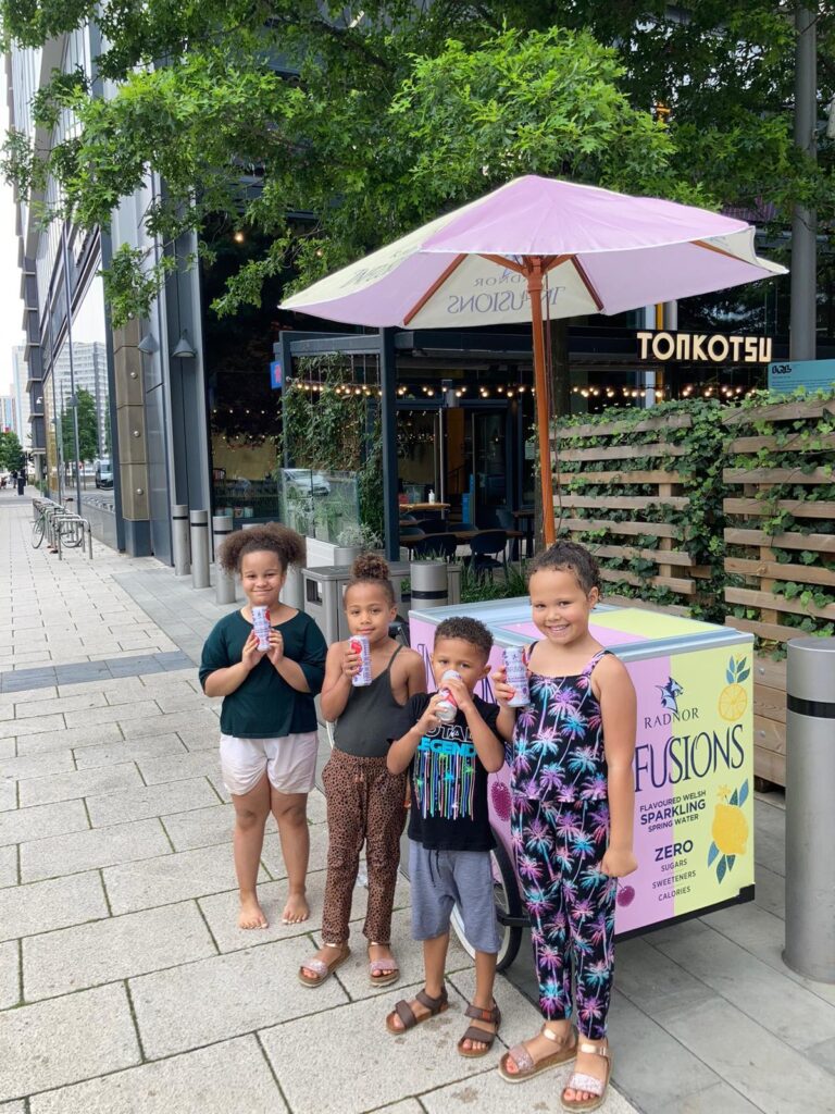 children enjoying drinks beside branded radnor fusions stand outdoors