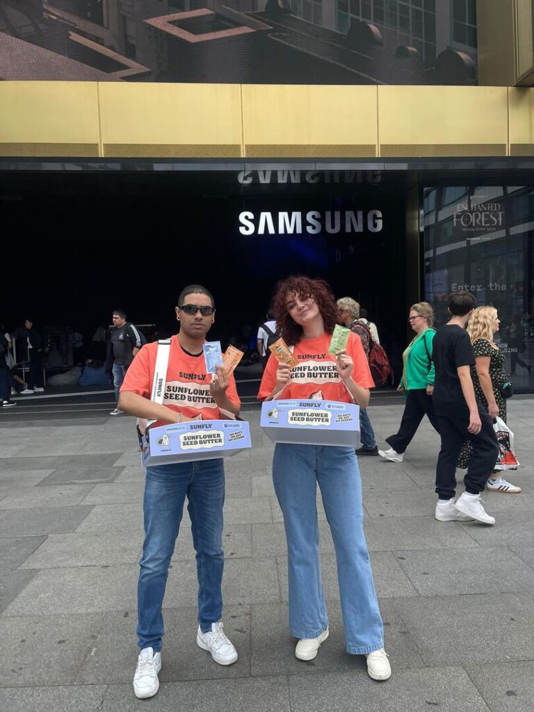 two promoters outside samsung store distributing product samples to passersby