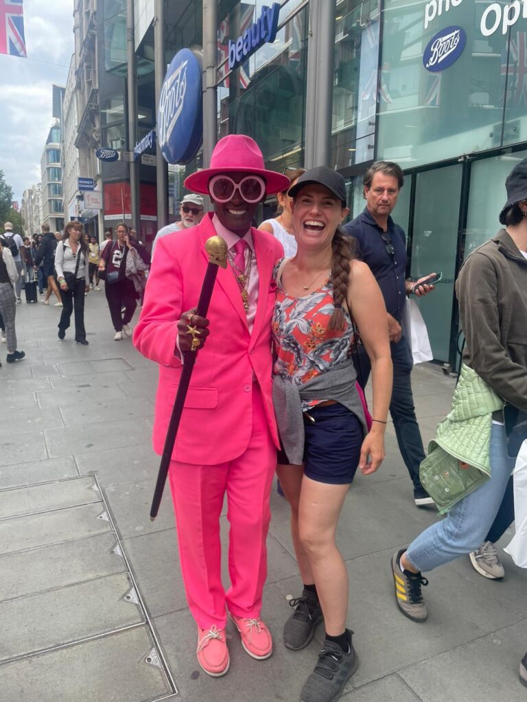 woman posing with man in bright pink suit on busy city street