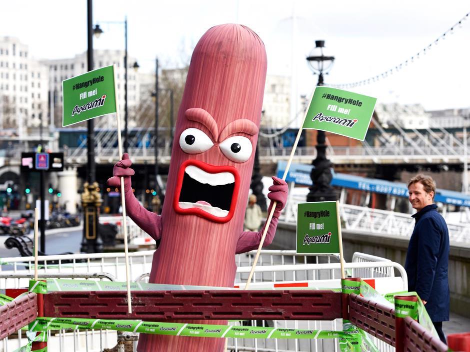 person in sausage costume holding protest signs on street