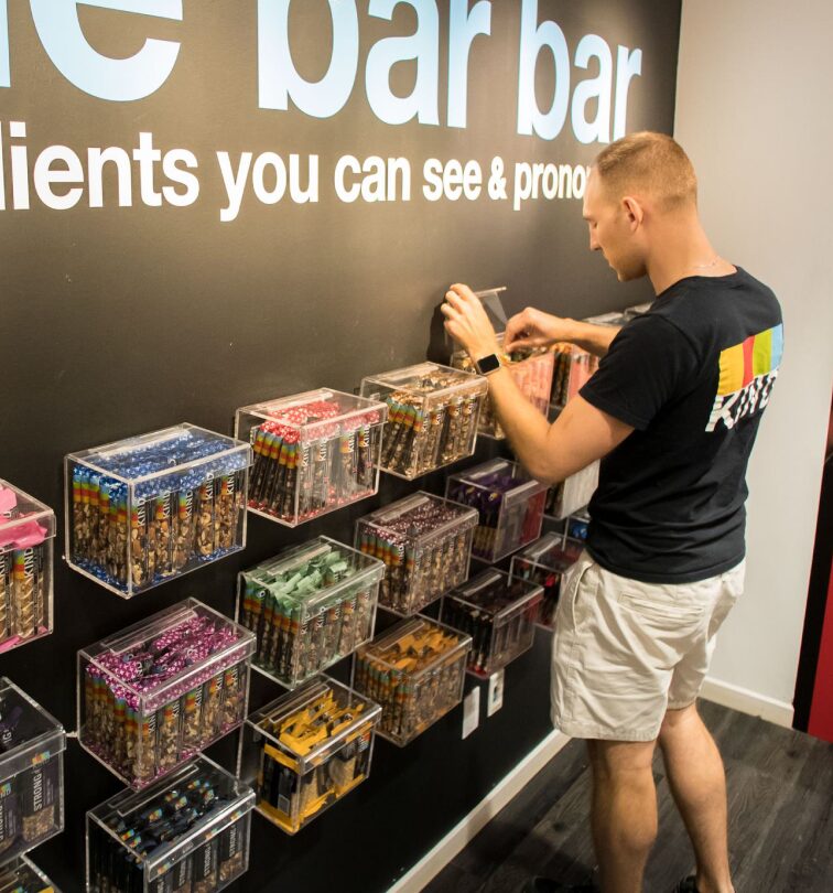 man arranging snack bars on display wall inside shop
